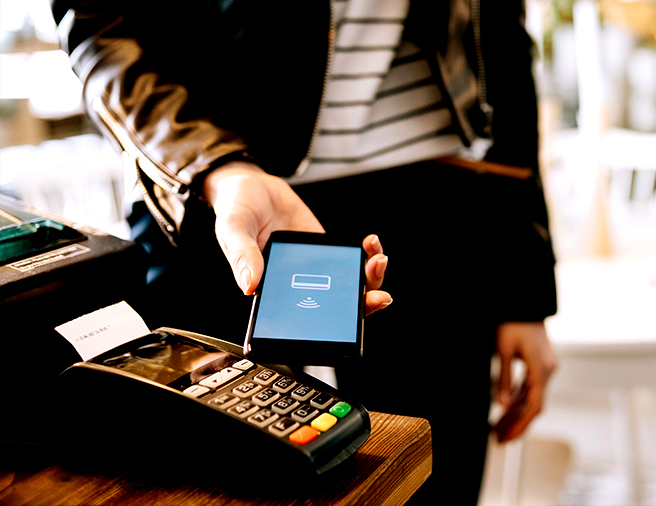 Man tapping his phone at a pay terminal